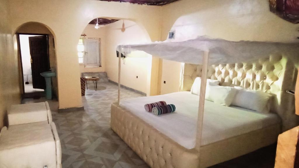 a bedroom with a large white bed with an umbrella at Baba Lao Hotel in Malindi