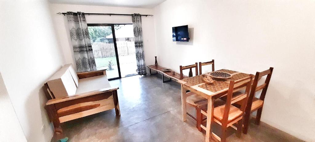 comedor con mesa, sillas y TV en Savanna Tree Apartments - self catering town center, en Livingstone