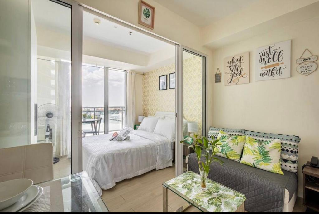 um quarto com uma cama, um sofá e um espelho em The Bahama Hammock - Azure PH em Manilla