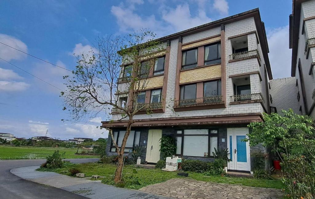 un edificio de apartamentos con un árbol delante de él en Cathy French House, en Dongshan