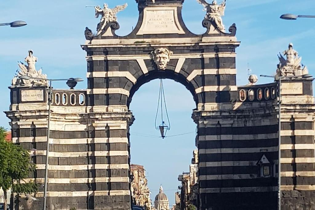 an arch with statues on top of a building at Vita in Catania