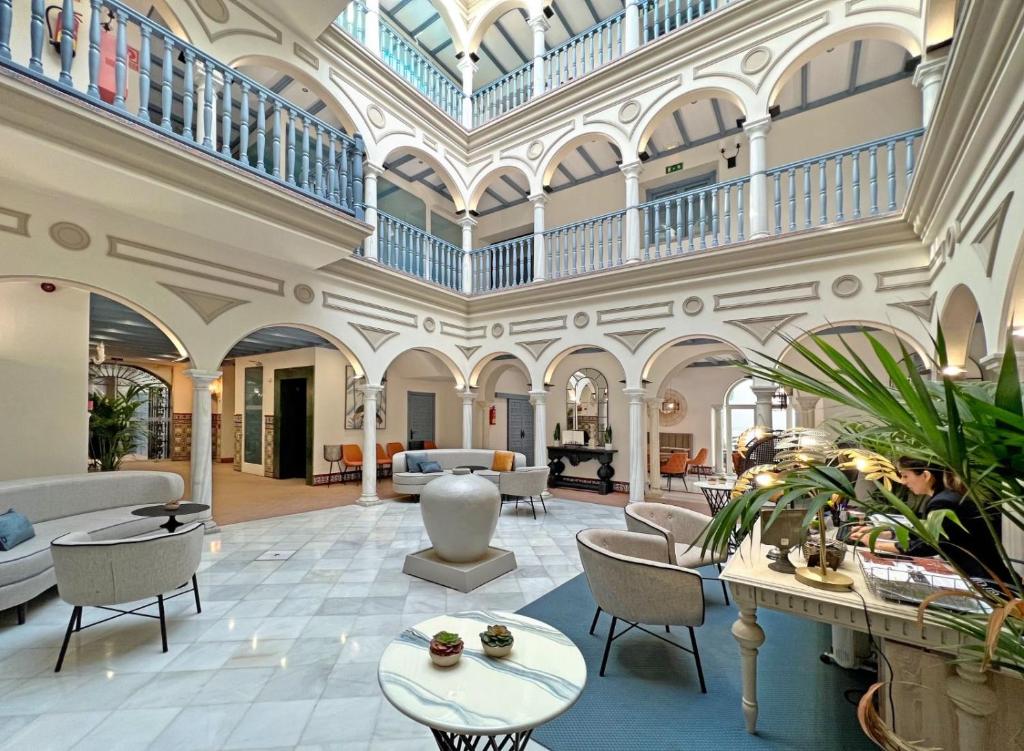 a large lobby with a large ceiling and tables and chairs at Itaca Sevilla by Soho Boutique in Seville