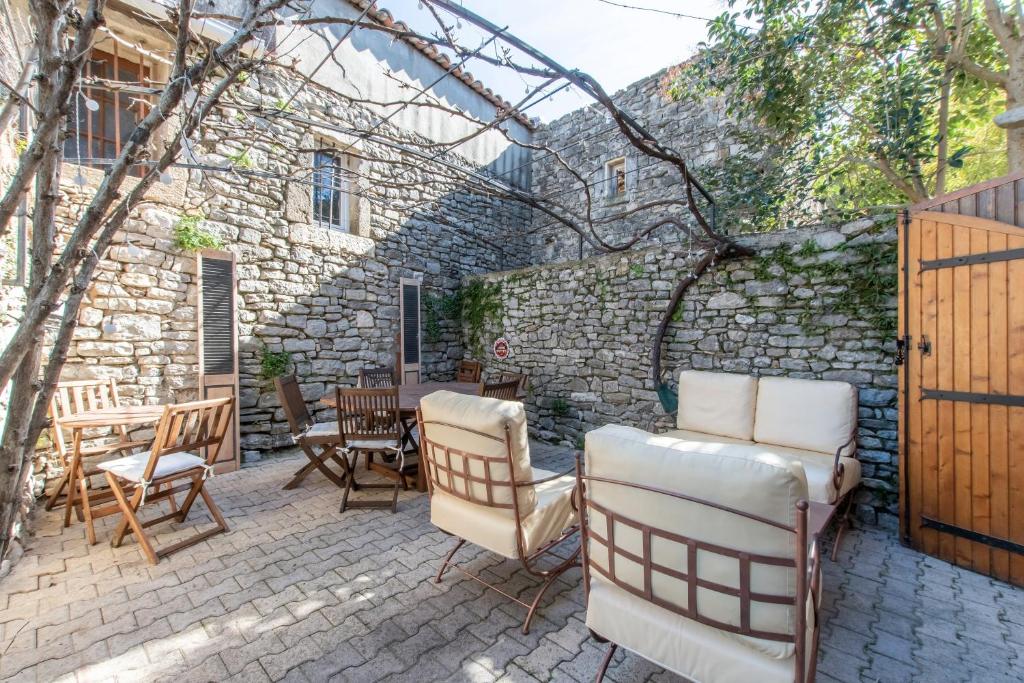 un patio con sillas, mesas y una pared de piedra. en Le Saint-Clémentois - Maison pour 6, en Saint-Clément