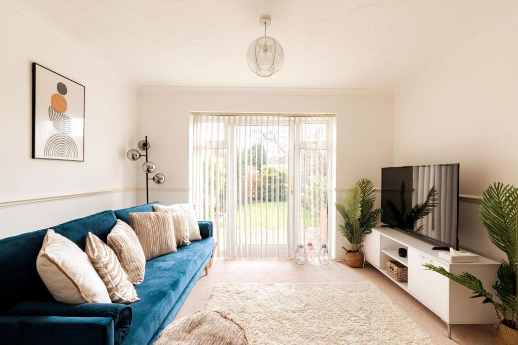 a living room with a blue couch and a tv at Surrey Stays - 2Bed house, 2 parking spaces, RH1, near Gatwick Airport in Redhill