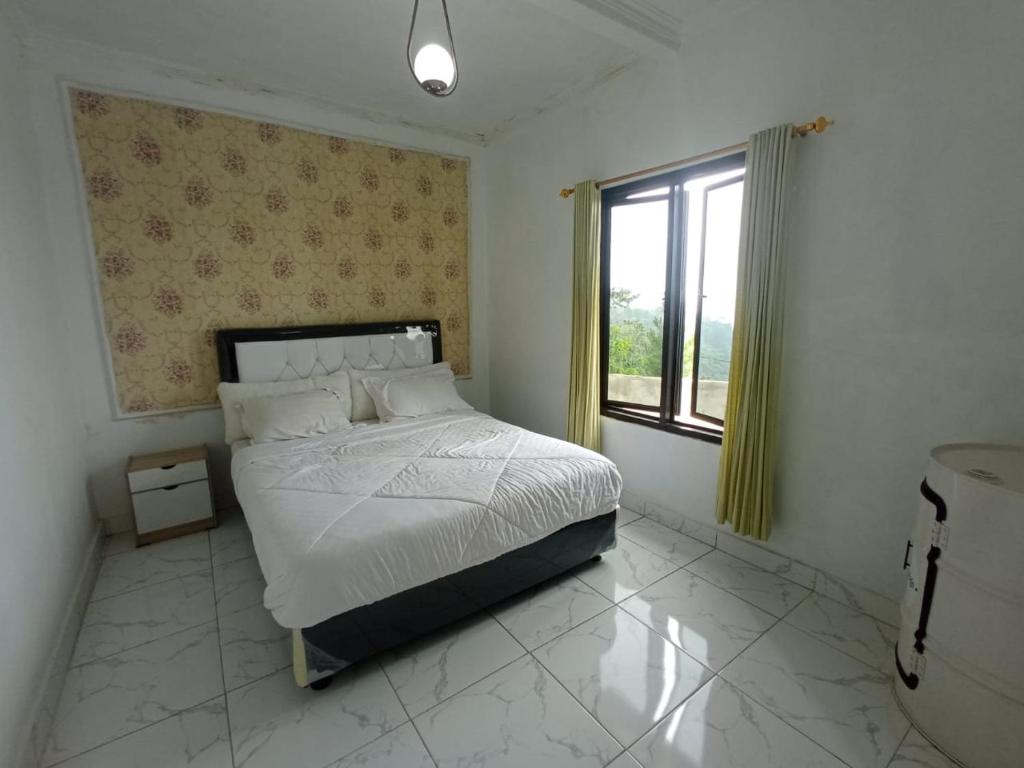 a bedroom with a large bed and a window at RD Cottage Valley in Bogor