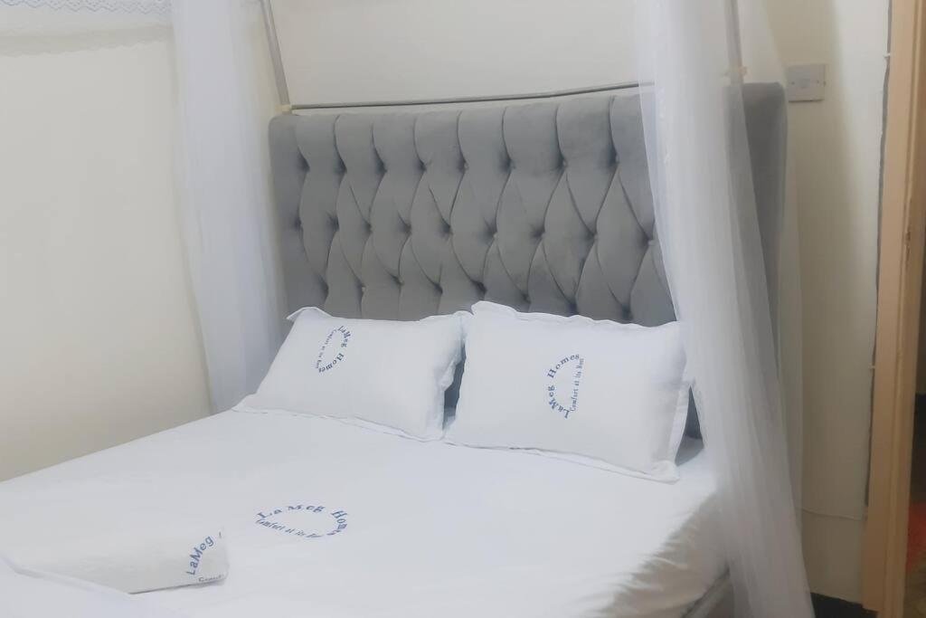 Una cama blanca con dos almohadas blancas. en LaMeg Homestay, en Nairobi