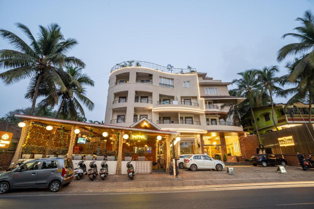 a hotel with cars parked in front of a building at Le Seasons Resort in Candolim