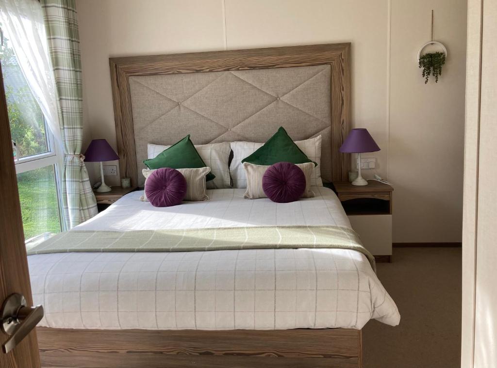 um quarto com uma cama grande com almofadas roxas e verdes em BRANWOOD Acorn Caravan Holidays Newquay em Newquay