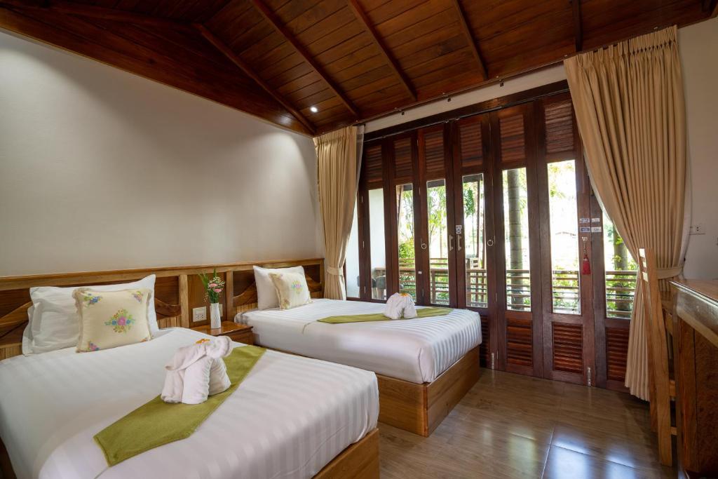 two beds in a room with windows at Madee Spa & Resort in Ban Khok Lo