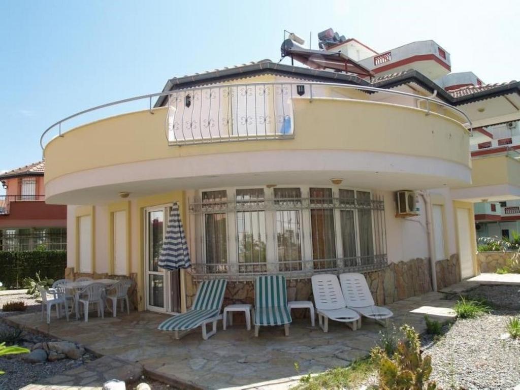 a house with a balcony with chairs and a table at Villa İlse in Avsallar