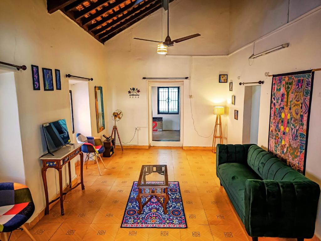 een woonkamer met een groene bank en een tafel bij Casa Brooklyn Portuguese Heritage in Saligao