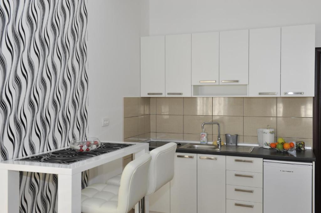 a kitchen with white cabinets and a black and white patterned wall at Apartment Jovana Nikšić in Nikšić