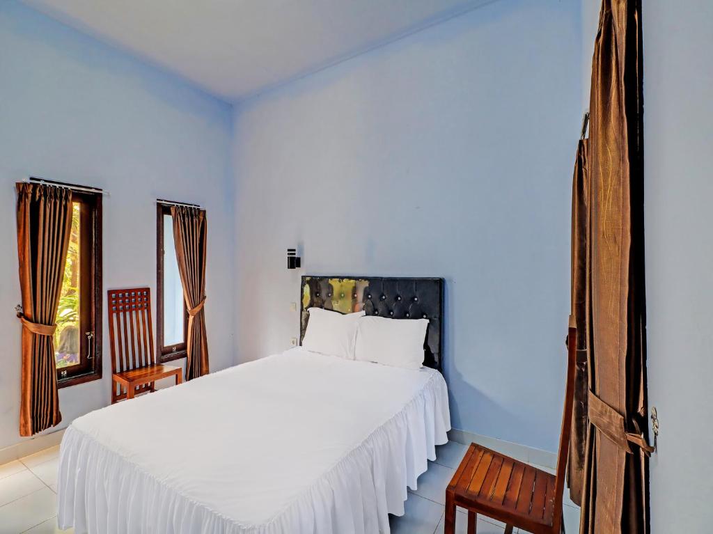 a bedroom with a white bed and two chairs at OYO 92401 Hotel Mustika in Mendaya