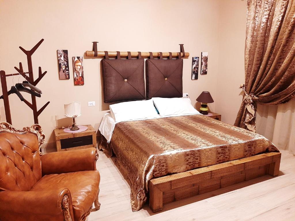 een slaapkamer met een groot bed en een stoel bij Carmen's Home in San Nicola La Strada
