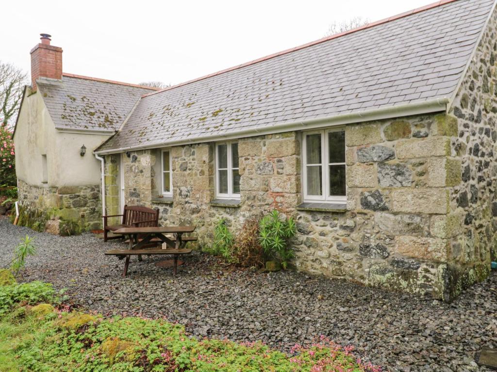 an old stone house with a picnic table in front of it at Swallows in Saint Keverne