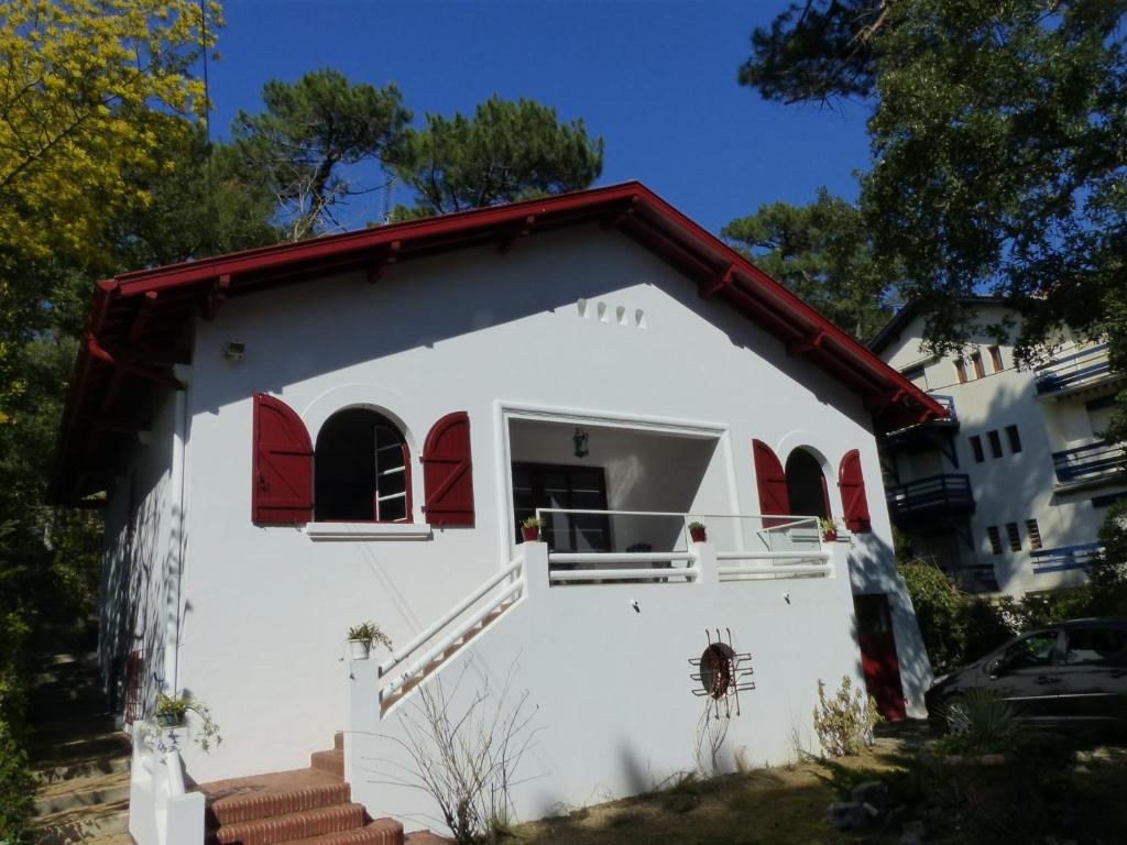 ein kleines weißes Gebäude mit roten Fenstern und Treppen in der Unterkunft Villa DOUS REPAOUS pour 5 personnes entre lac et océan in Soorts-Hossegor