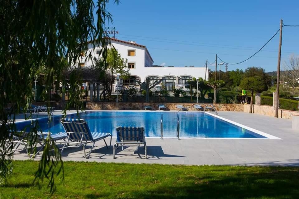 a pool with two chairs and a house in the background at Ca La Maria in Tordera