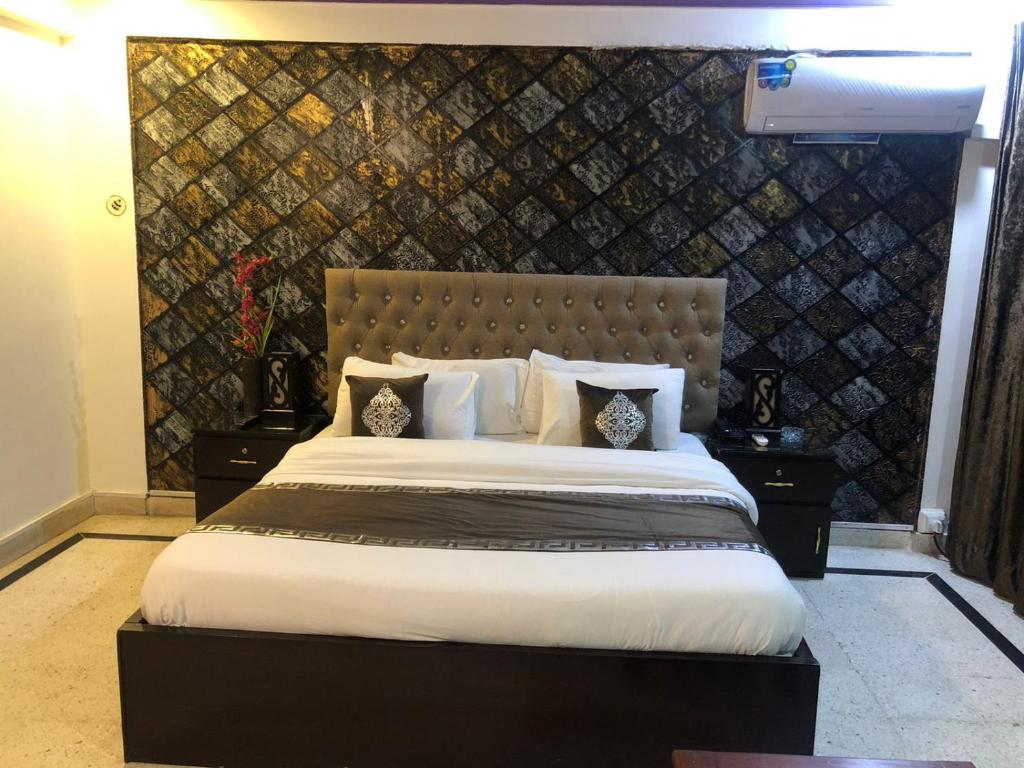 a bedroom with a large bed and a wall at Muzaffarabad View Motel in Muzaffarabad