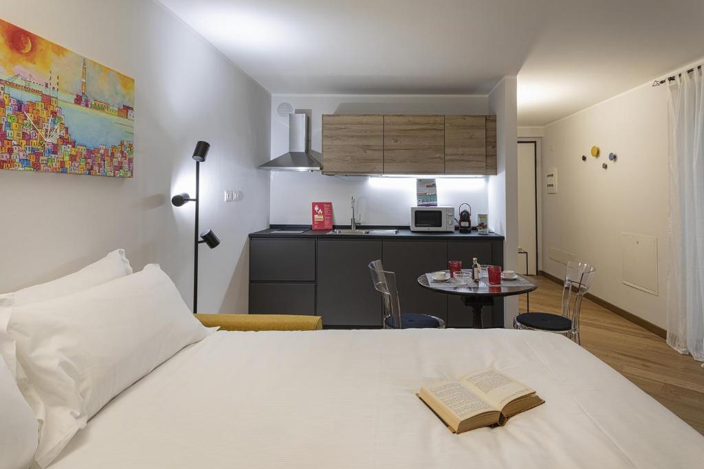 um quarto com uma cama branca com um livro em Superba Studio by Wonderful Italy em Gênova