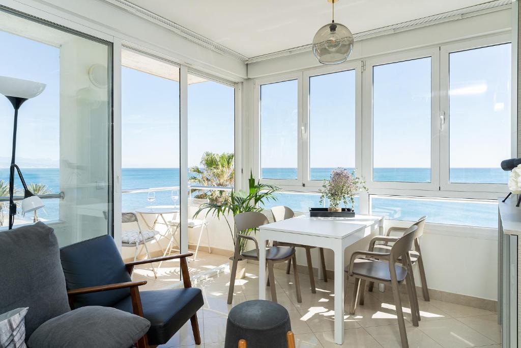 ein Wohnzimmer mit einem Tisch, Stühlen und Meerblick in der Unterkunft MONKÓ ON THE ROCK in Torremolinos