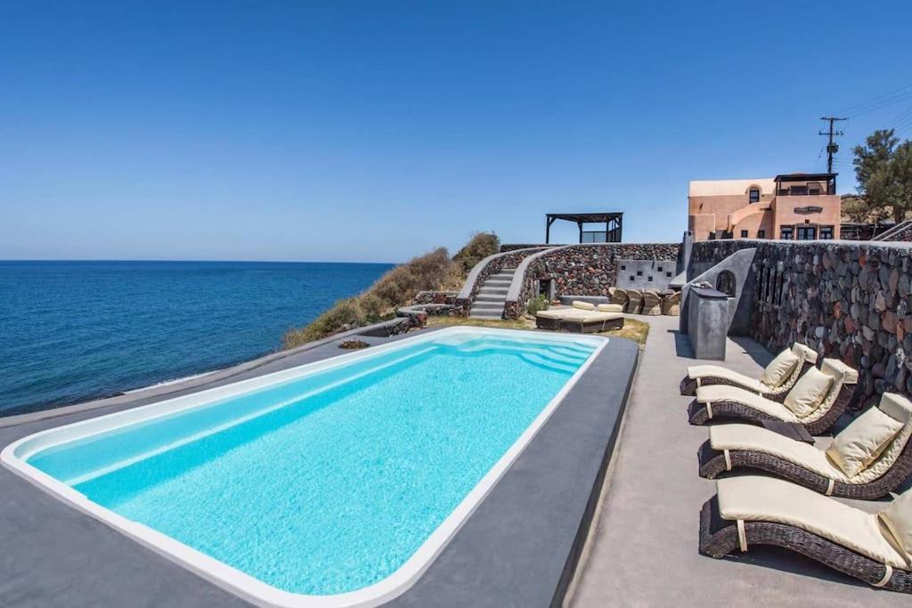a swimming pool with lounge chairs and the ocean at Ramni House: Private Villa with pool by the Sea in Oia
