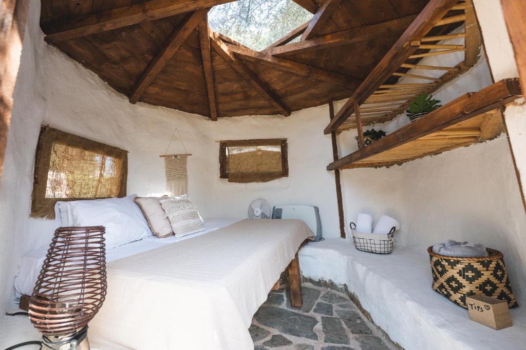 1 dormitorio con cama blanca y techo de madera en Nisi Glamping, en Paralía Rachon