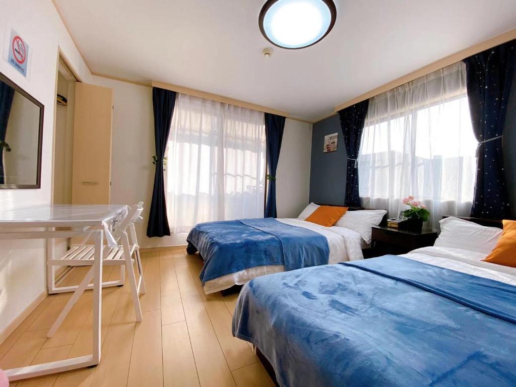 a room with two beds and a table and windows at D27-Outstanding convenience 4DK/ Shinjuku Okubo in Tokyo