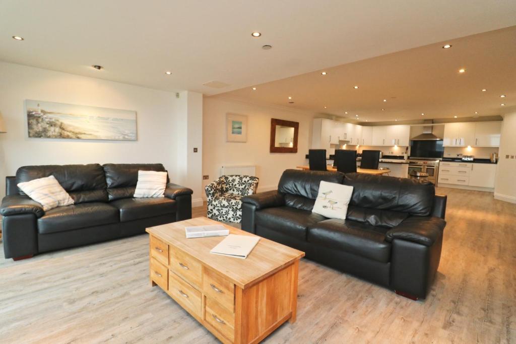 a living room with black leather furniture and a table at BY THE BEACH, spacious apartment in Saint Merryn