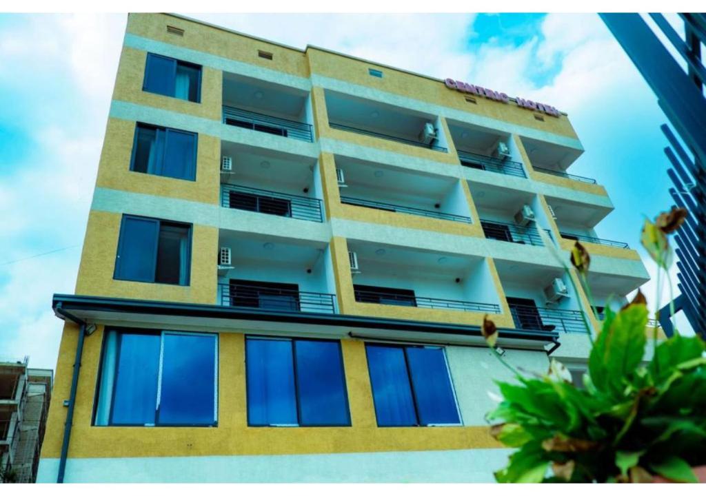 a yellow and white building with blue windows at Centric Hotel in Kigali