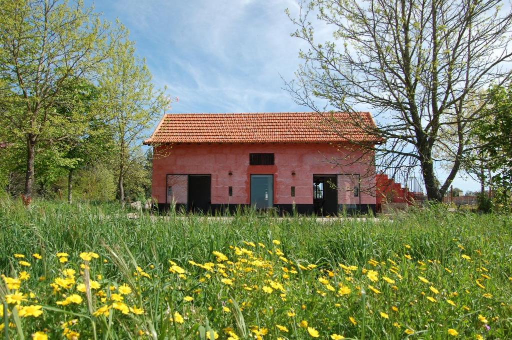 um pequeno edifício vermelho num campo de flores em Casa de Cabanelas em Bustelo