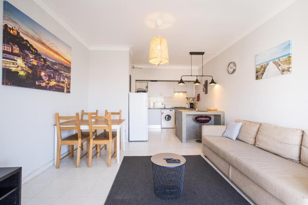ein Wohnzimmer und eine Küche mit einem Sofa und einem Tisch in der Unterkunft Hoso Apartments T1 in Costa da Caparica
