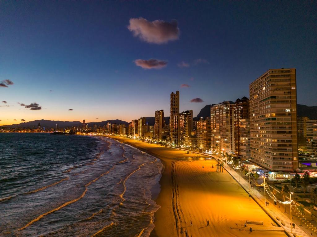 uma praia com edifícios e o oceano à noite em Beautiful Parque Loix 4 bedroom apartment shared pool, tennis court em Benidorm