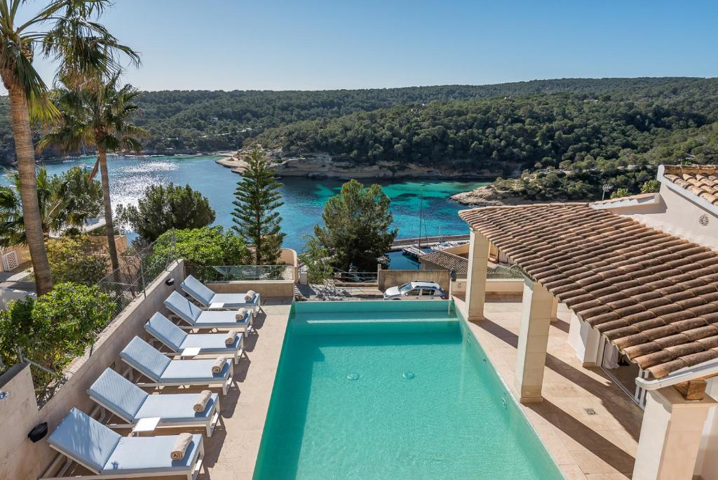 a pool with chairs and a view of the water at Luxury Villa with panoramic sea views in Sol de Mallorca