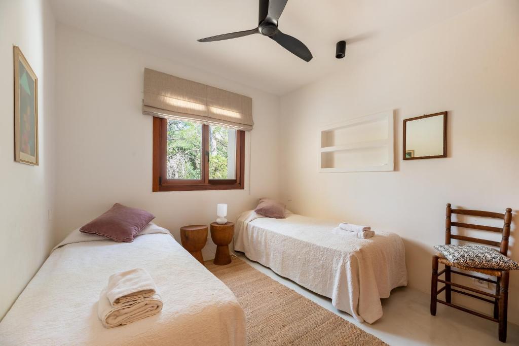 two beds in a bedroom with a ceiling fan at Casa Juliarina in Sant Josep de sa Talaia