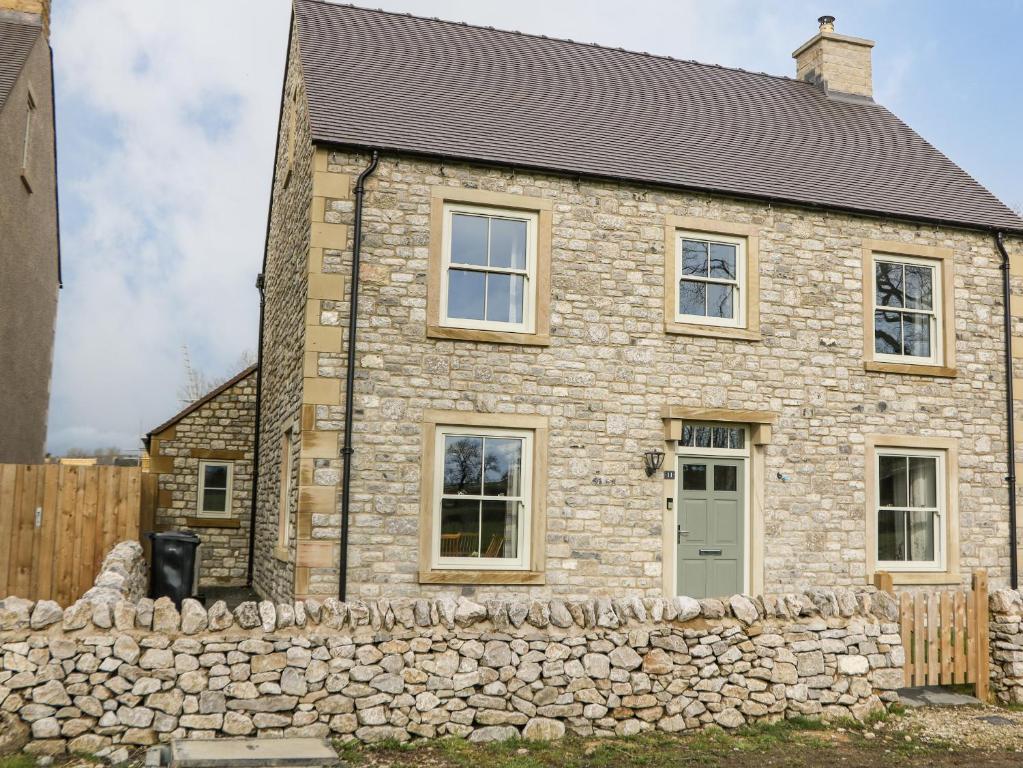 a stone house with a stone wall at Dove Meadows House in Buxton