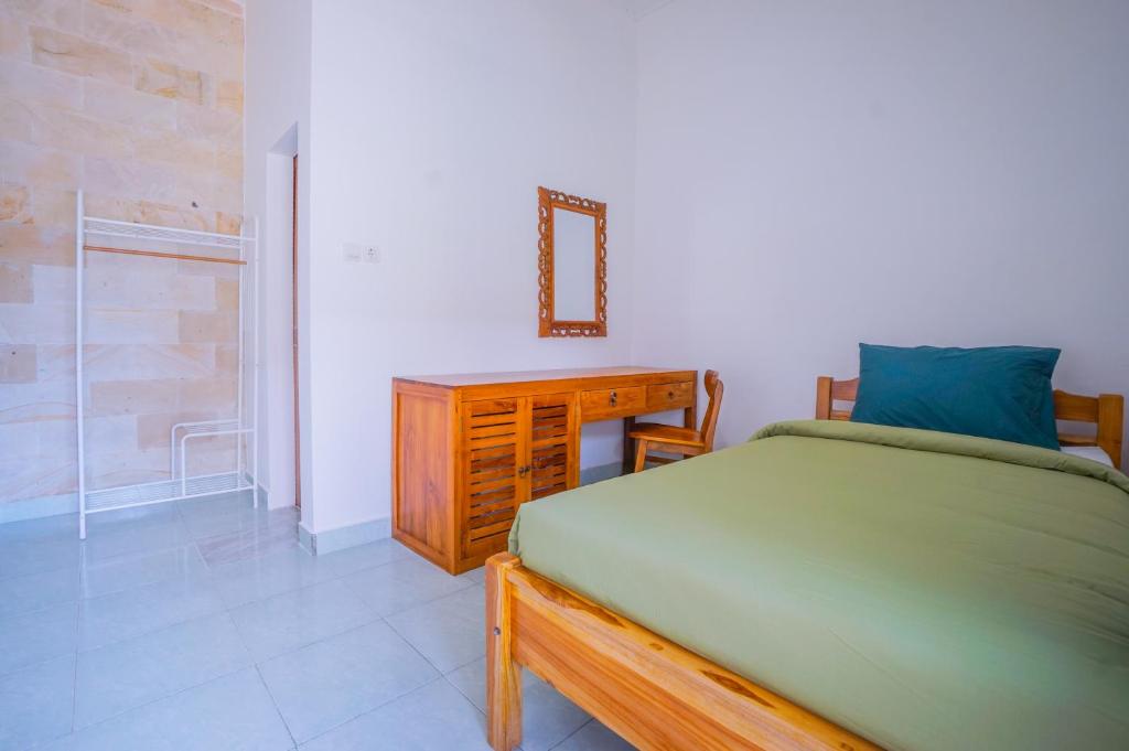 a bedroom with a bed and a dresser and a mirror at Kos Bulan Bali in Kuta