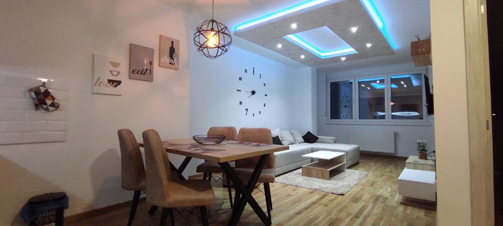 uma sala de jantar e sala de estar com uma mesa e um sofá em Apartman Jasmina em Subotica