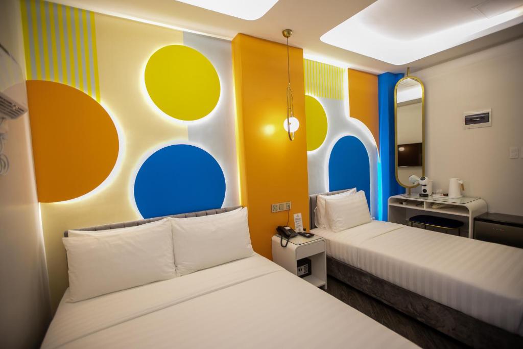 two beds in a room with colorful walls and a sink at M.Y. Hotel in Dumaguete