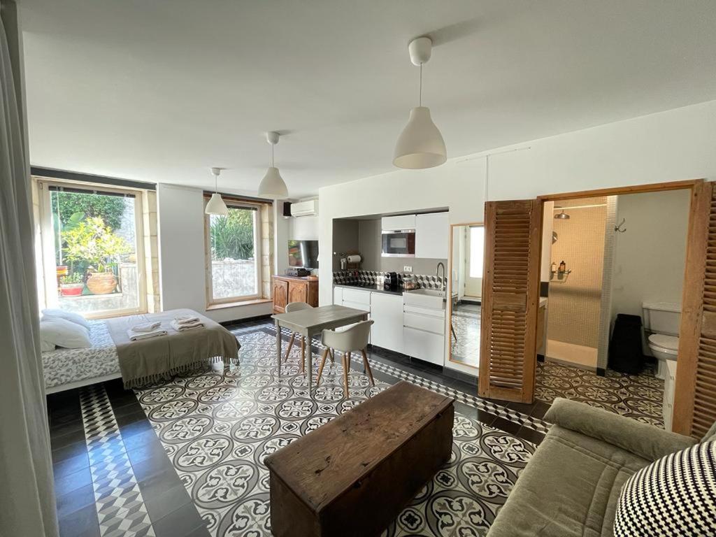 a living room with a bed and a kitchen at Le bonheur de la campagne à la ville - Grand studio en plein coeur de la ville in Nîmes