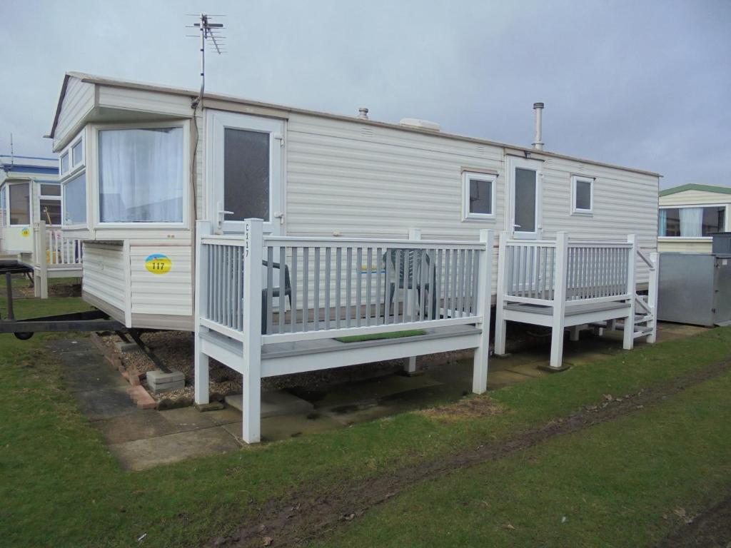 a white mobile home with a porch and two benches at 6 Berth on Golden Sands (Westbrook Tahiti) in Ingoldmells