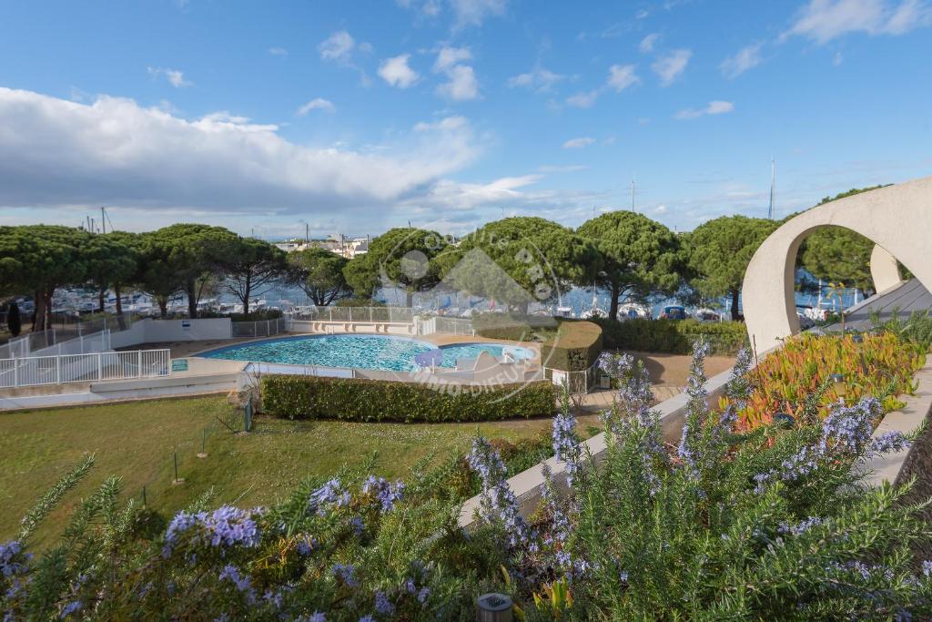 un jardin avec une piscine et des fleurs dans l'établissement AS22429 - P2 Cabine avec terrasse et jardin privatif, au Grau-du-Roi