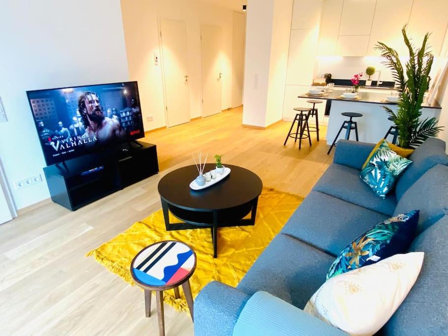 ein Wohnzimmer mit einem blauen Sofa und einem TV in der Unterkunft Luxury Brand New Flat with Terrace & Parking - RTL1 in Luxemburg (Stadt)