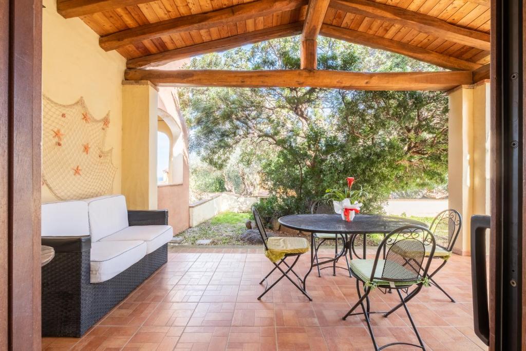 un patio con mesa, sillas y sofá en Villetta Erica en Tanaunella