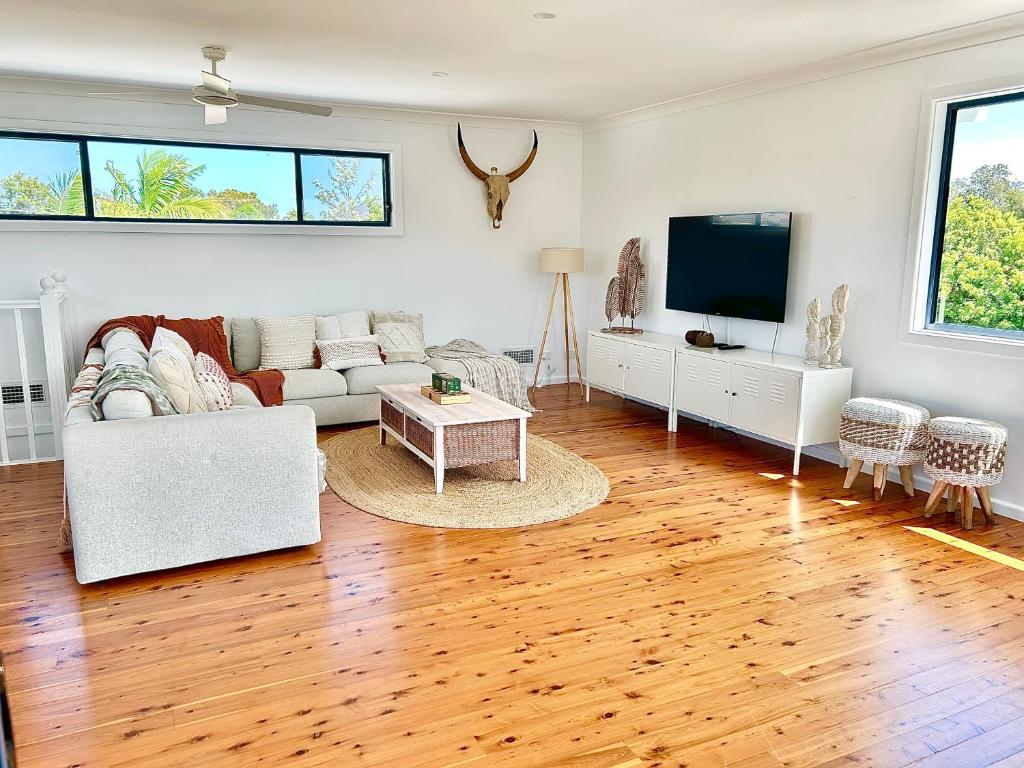 a living room with a couch and a tv at Long Jetty Lake House in Long Jetty