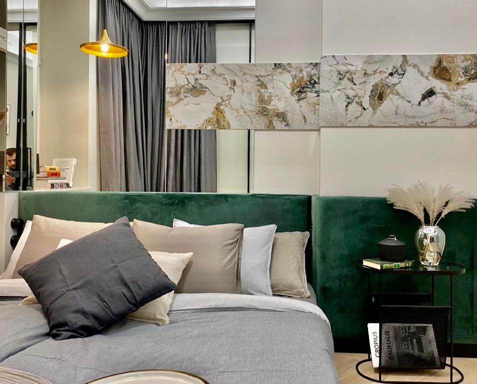 a bedroom with a bed with a green headboard at AK Apartments in Warsaw