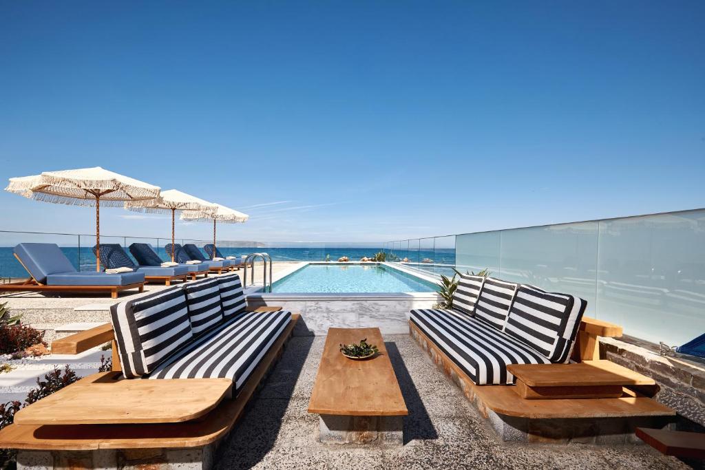 a patio with benches and a swimming pool at Rodo Seafront Villa with Heated private pool and jacuzzis by Volta Suites and Villas in Kokkíni Khánion