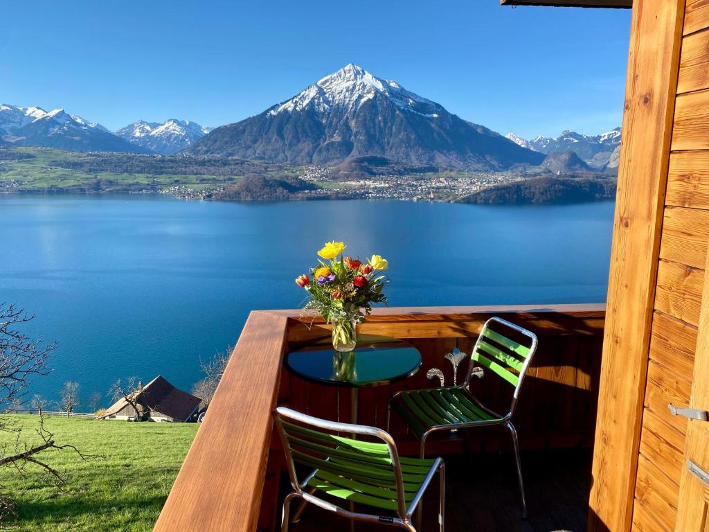 uma mesa e cadeiras num deque com vista para uma montanha em CHALET EGGLEN "Typical Swiss House, Best Views, Private Jacuzzi" em Sigriswil