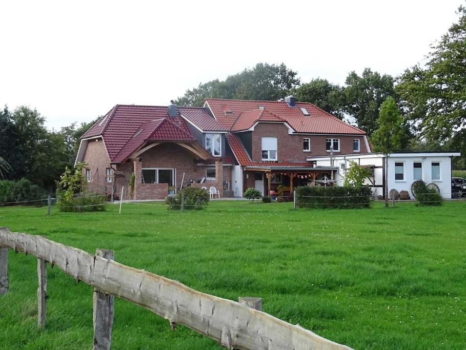 ein großes Haus mit einem Zaun auf einem Feld in der Unterkunft Charmante Ferienwohnung in idyllischer Lage in Jever