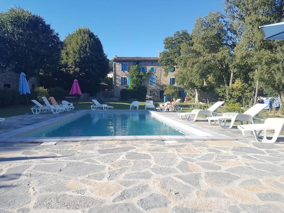 una piscina con tumbonas blancas y una casa en grand gîte de charme en Cévennes, en Fressac