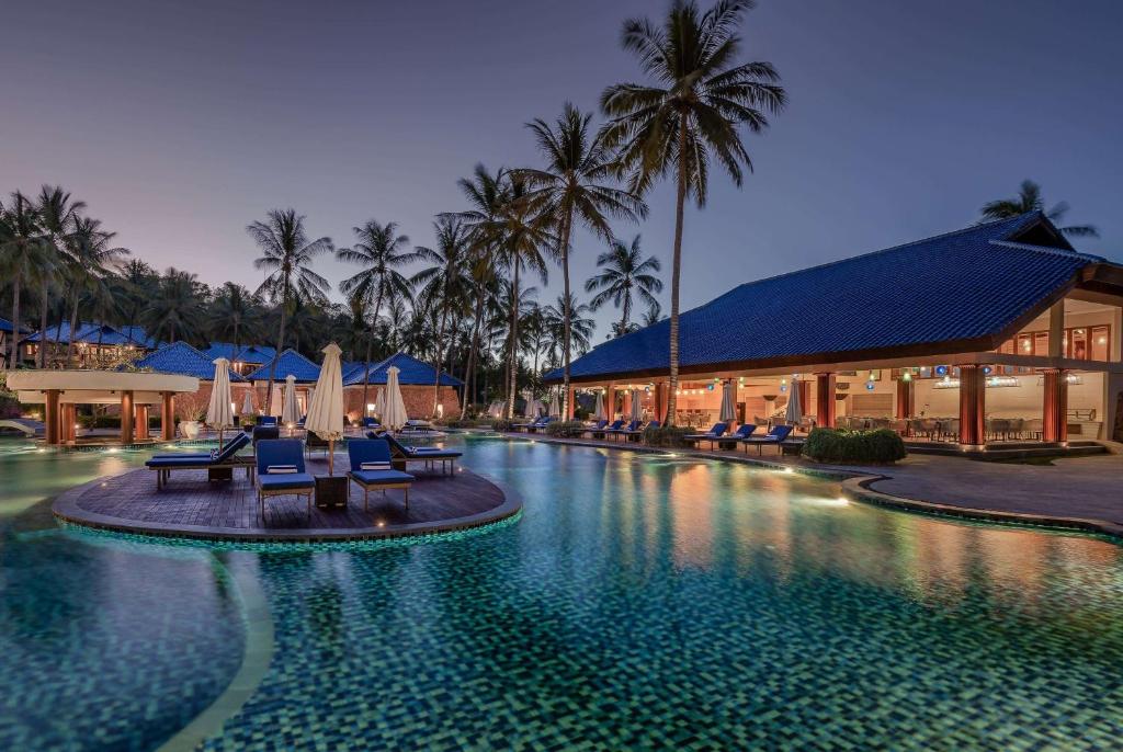 a resort swimming pool with chairs and a building at Sundancer Residences and Villas Lombok in Sekotong